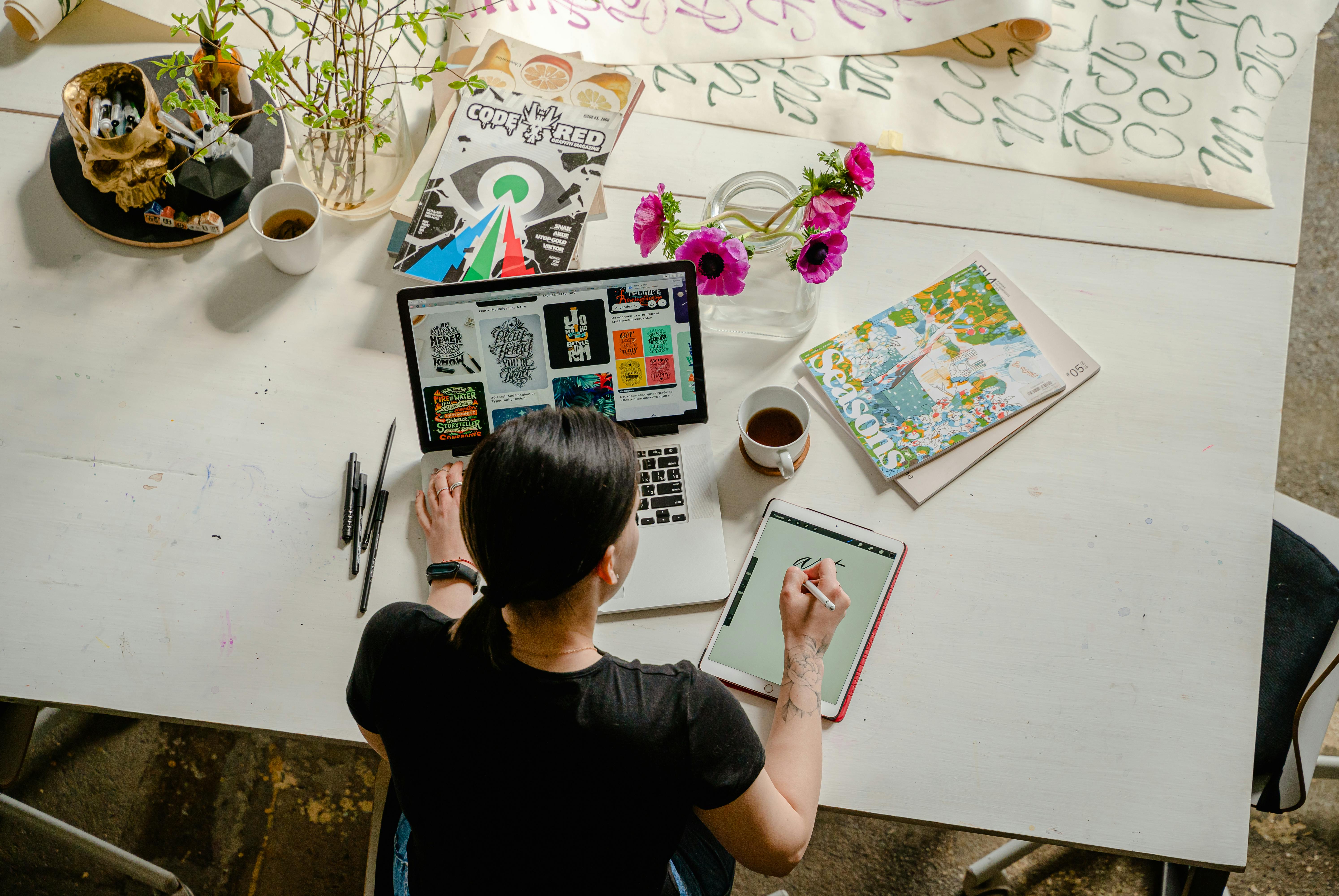 photo of a lady overtop of a laptop and paper sitting at a table. Showcasing tech essentials